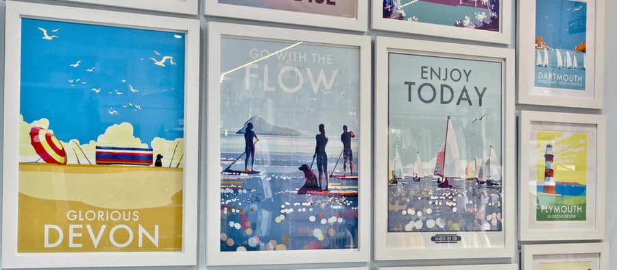 A wall of Becky Bettesworth seaside prints inside Bertie and Crew, including Brixham harbour scenes.